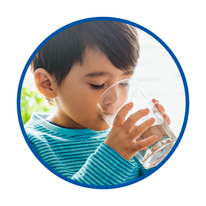 a young boy drinking a glass of water