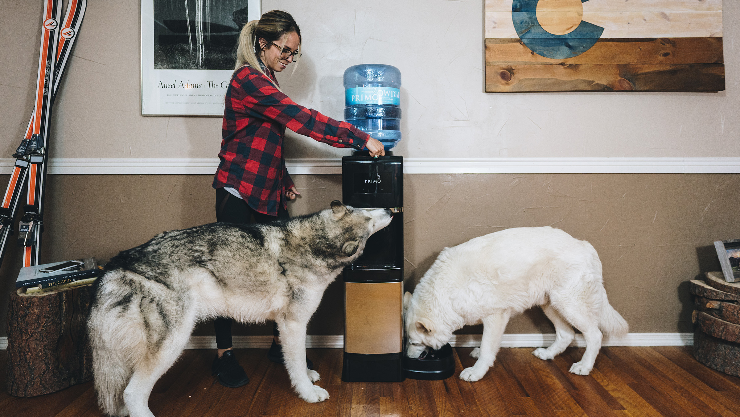 A woman dispenses water for her two huskies